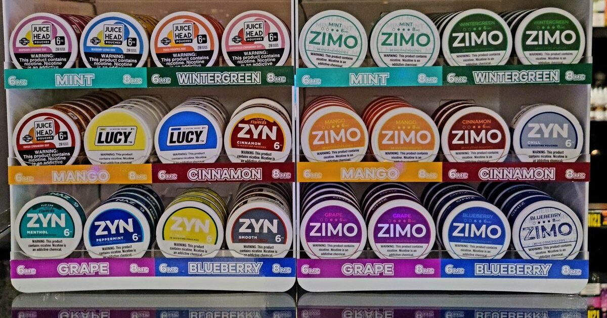 Assorted nicotine pouch tins in various flavors arranged on a wooden surface